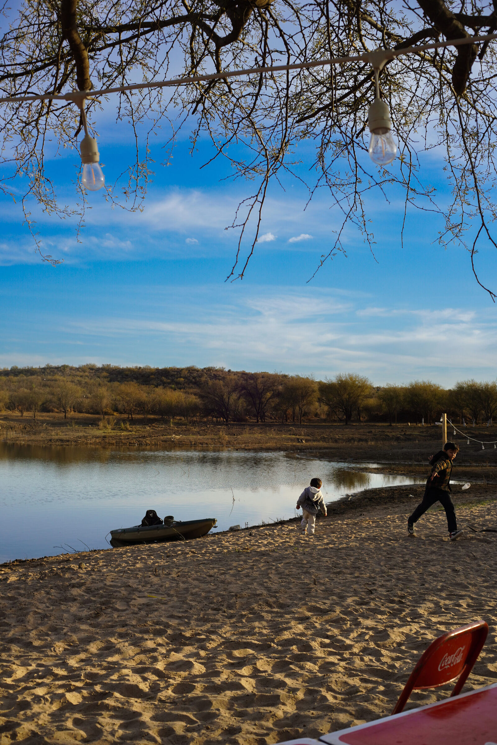 Playa del lago de Ciudad Norte con niños jugando al atardecer